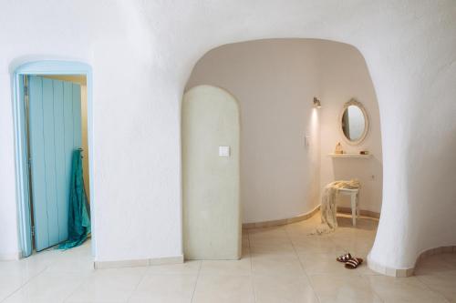 un pasillo con una pared blanca y una puerta azul en SantoCaves en Akrotiri