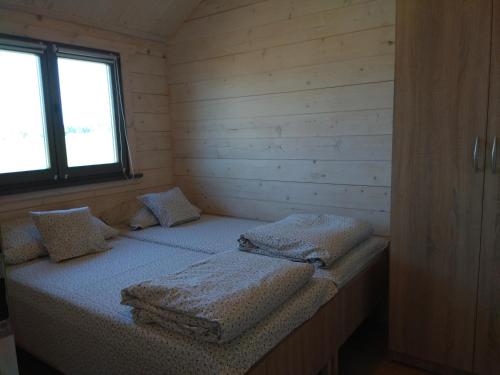 a room with two beds in a small room with a window at Domki Nad Stawem Mazury in Mrągowo