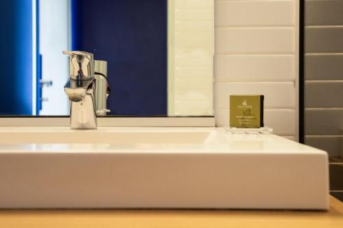 a bathroom sink with a faucet and a mirror at Hotel Paradou Mediterranee, BW Signature Collection by Best Western in Sausset-les-Pins