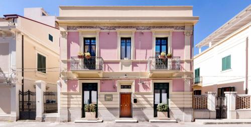 レッジョ・ディ・カラブリアにあるVilla Laviniaのピンクの建物(バルコニー2つ、ドア1つ付)