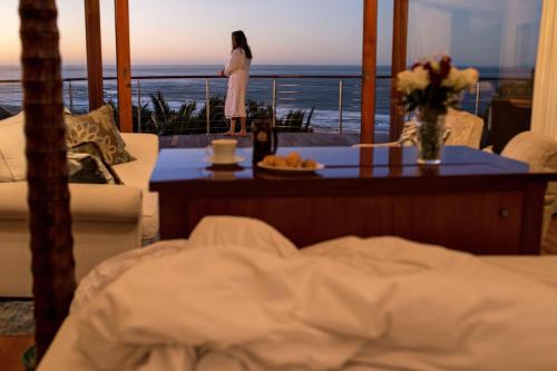 a woman standing on a balcony looking out at the ocean at Oceana Beach and Wildlife Reserve in Port Alfred