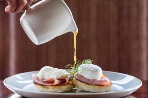 a person pouring cream on two sandwiches on a plate at Oceana Beach and Wildlife Reserve in Port Alfred
