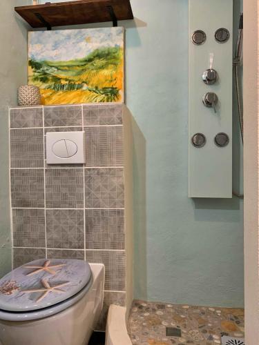 a bathroom with a toilet and a painting on the wall at Casa Mandarina centro de Cómpeta con chimenea y terraza con vistas By AndaraHolidays in Cómpeta