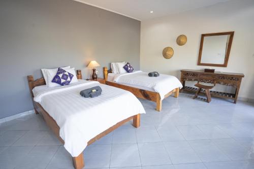 2 camas en una habitación con espejo y mesa en Bali Dive Resort Amed en Amed