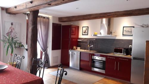 une cuisine équipée de placards rouges et d'appareils en acier inoxydable dans l'établissement Gite de la Petite Venise du Gatinais, à Pannes