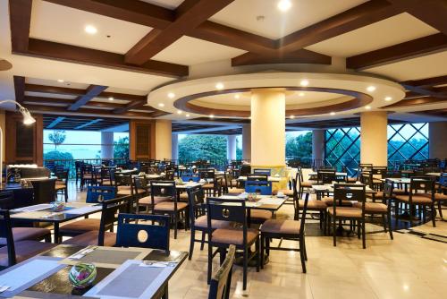 a restaurant with tables and chairs in a room at Long Beach Garden Hotel & Pavilions in North Pattaya