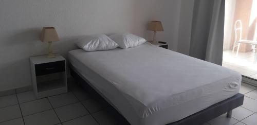 1 cama con sábanas blancas y almohadas en el dormitorio en Cala di Sognu, en Moriani Plage