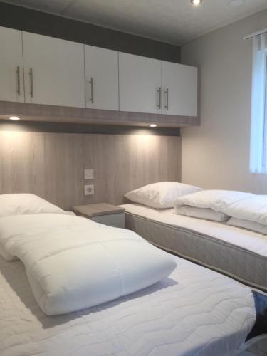 a bedroom with two beds and white cabinets at Tannisby Camping in Tversted