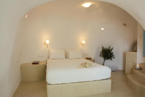 Un dormitorio con una cama blanca con un animal de peluche. en SantoCaves en Akrotiri
