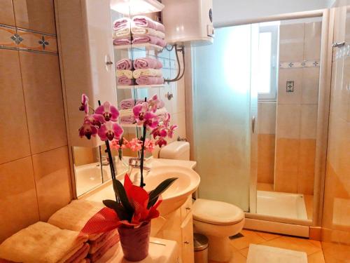 uma casa de banho com um WC e um lavatório com flores cor-de-rosa em Apartmants Jušić em Opatija