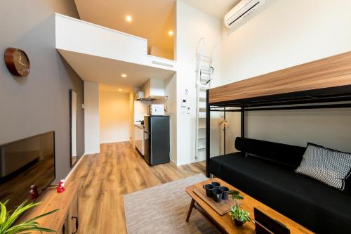 een woonkamer met een zwart bed en een keuken bij TRIP POD CHIYO A in Fukuoka