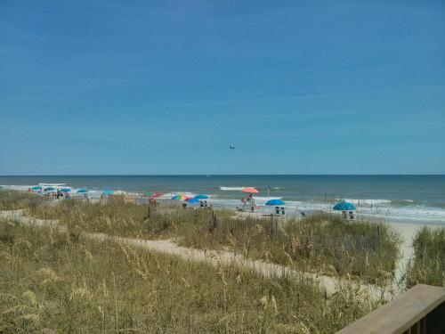 a beach with umbrellas and people on the beach at Tropical Seas Hotel in Myrtle Beach