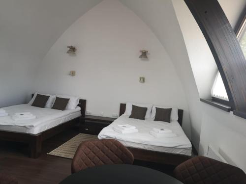 two beds in a room with two chairs and two windows at Hunnia - Huntanya in Vlăhiţa