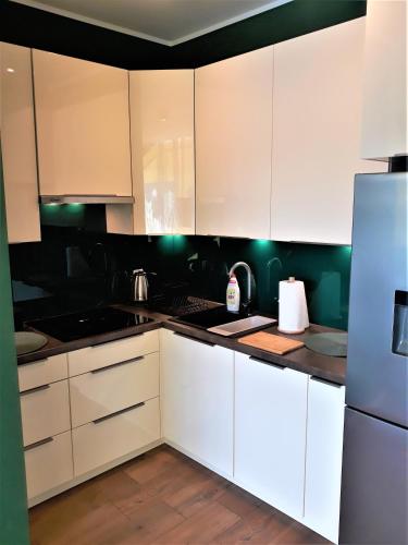 a kitchen with white cabinets and a refrigerator at Mazurskie Klimaty Tatarak in Olsztyn