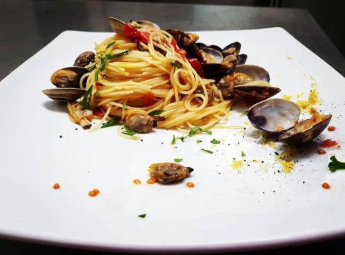 a white plate with pasta and mussels on it at Hotel Rodà in Panarea