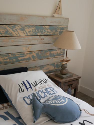 a blue pillow on a bed next to a lamp at Le Carpe Diem in La Forêt-Fouesnant