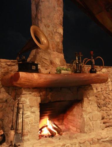 a stone fireplace with a wooden board on top of it at Pousada Pedra Grande in Serra de São Bento