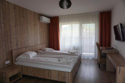 a bedroom with a large bed and a window at Pensiunea Patru Anotimpuri in Sasca Română