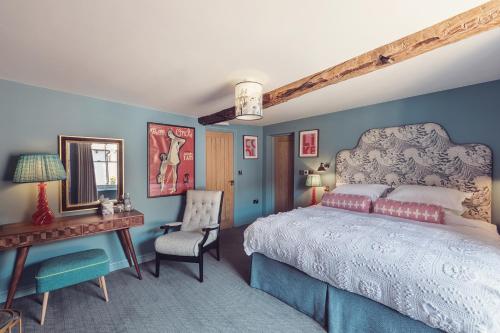 een slaapkamer met een bed, een bureau en een stoel bij The New Inn in Carnforth