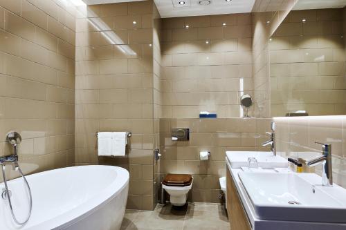 a bathroom with a tub and a toilet and a sink at Tallink Spa & Conference Hotel in Tallinn