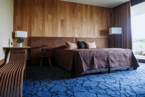 a bedroom with a bed with a wooden wall at Lajvér Borbirtok in Szálka