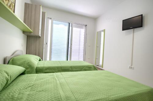 a bedroom with three green beds and a flat screen tv at Jacuzzi Holiday Homes by LoveSud in Leuca