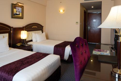 a hotel room with two beds and a table with a lamp at Flower Garden Hotel in Hanoi