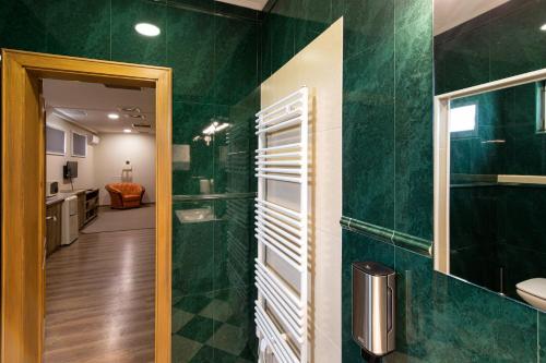 a bathroom with a green tiled wall at Napfény Panzió és Rendezvényház in Kecskemét