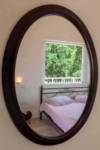 a mirror in a bedroom with a bed and a window at VillaEvaNafplion in Paralía Iríon