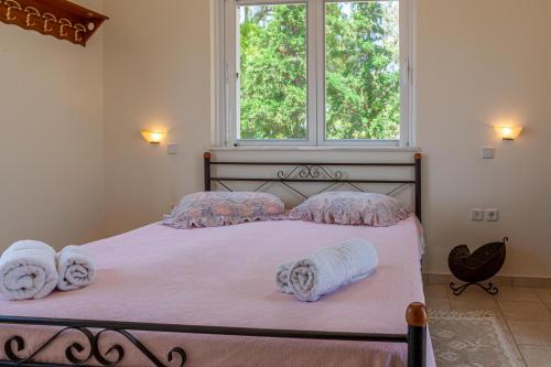 a bedroom with a bed with towels and a window at VillaEvaNafplion in Paralía Iríon