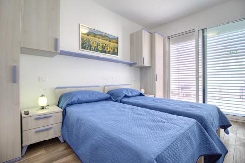 a bedroom with a bed with blue sheets and a window at Jacuzzi Holiday Homes by LoveSud in Leuca
