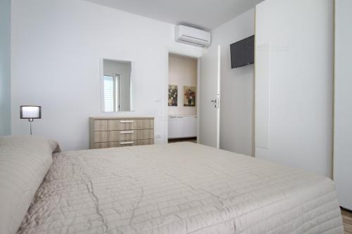 a white bedroom with a bed and a television at Jacuzzi Holiday Homes by LoveSud in Leuca