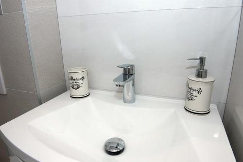 a bathroom sink with two cups and a faucet at Apartments Drago Kovačić in Omiš