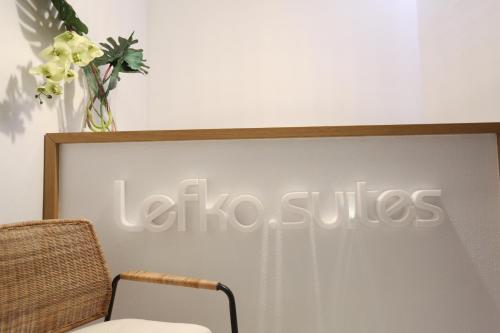 een bord dat zegt la suites op een muur met een stoel bij Lefko Suites in Hanioti