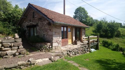 una pequeña casa de piedra con una pared de piedra en Les Grandes Fontaines en La Longine