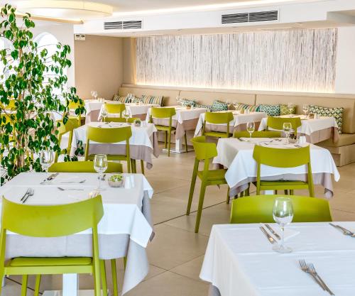 a restaurant with white tables and yellow chairs at R2 Bahia Cala Ratjada - Adults Only in Cala Ratjada