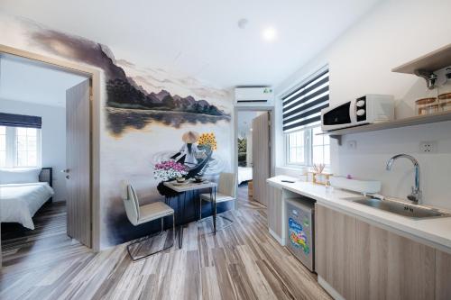 a kitchen with a painting of a woman sitting at a desk at Su Casa Hanoi Old Quarter in Hanoi