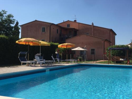 a swimming pool with chairs and umbrellas next to a building at Podere Casalpiano in Campiglia Marittima