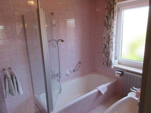 y baño con bañera, ducha y lavamanos. en Gästehaus zur Brücke en Waging am See