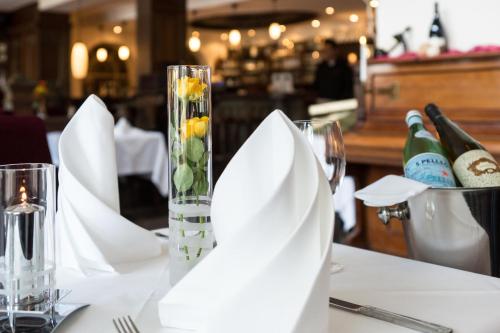 a table with white plates and a vase with flowers at Hotel Holsteiner Hof - Timmendorfer Strand in Timmendorfer Strand