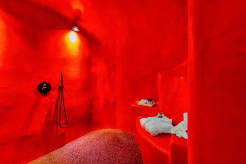 a red room with a bathroom with a red wall at Diamond Luxury Suites Collection in Oia