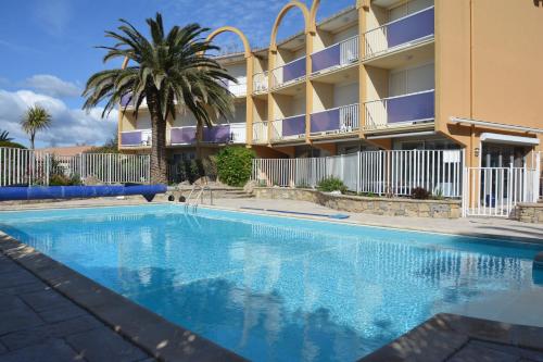 a swimming pool in front of a building at Hotel Albizzia in Valras-Plage