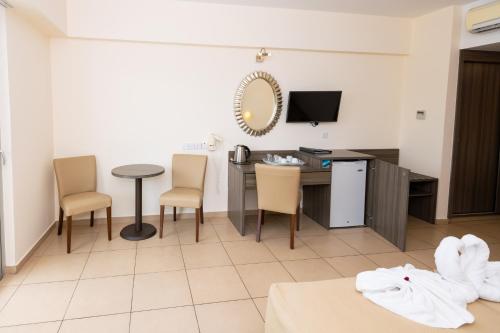 a room with a desk and a table and chairs at Tofinis Hotel in Ayia Napa