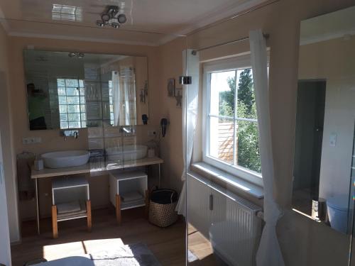 baño con lavabo, espejo y ventana en Mama Roserl, en Hauzenberg