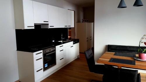 a kitchen with white cabinets and a table and a dining room at Appartement Mountainview in Saalbach Hinterglemm