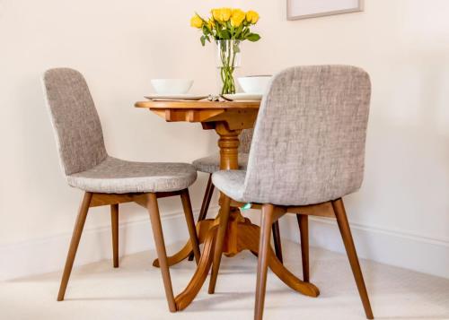 ヘンリー・イン・アーデンにあるLittle George, Henley-in-Arden Luxury Apartmentの花瓶付きの木製テーブルの椅子2脚