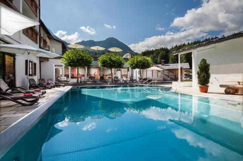 a swimming pool with blue water in a house at Alm- & Wellnesshotel Alpenhof in Schönau am Königssee
