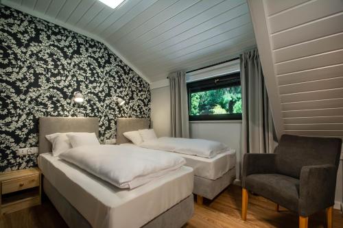 a bedroom with two beds and a chair at Tawerna Kaszubska in Ostrzyce