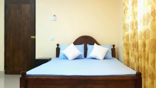 Schlafzimmer mit einem Bett mit blauer Bettwäsche und weißen Kissen in der Unterkunft Nimal's Home in Anuradhapura