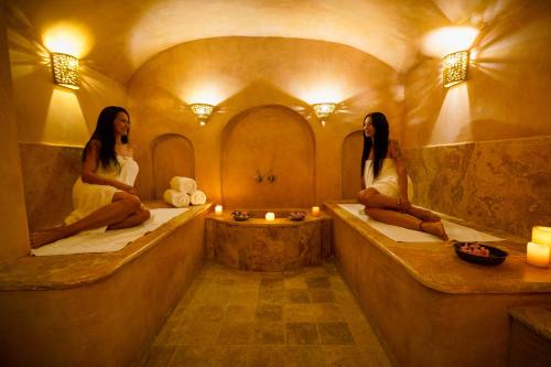 two women sitting on tubs in a room with mirrors at The Way Inn - Boutique Suites in Safed